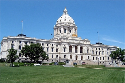 [ai] The Minnesota State Capitol building, featuring a large dome and classical architecture, surrounded by green grass and trees under a clear blue sky.